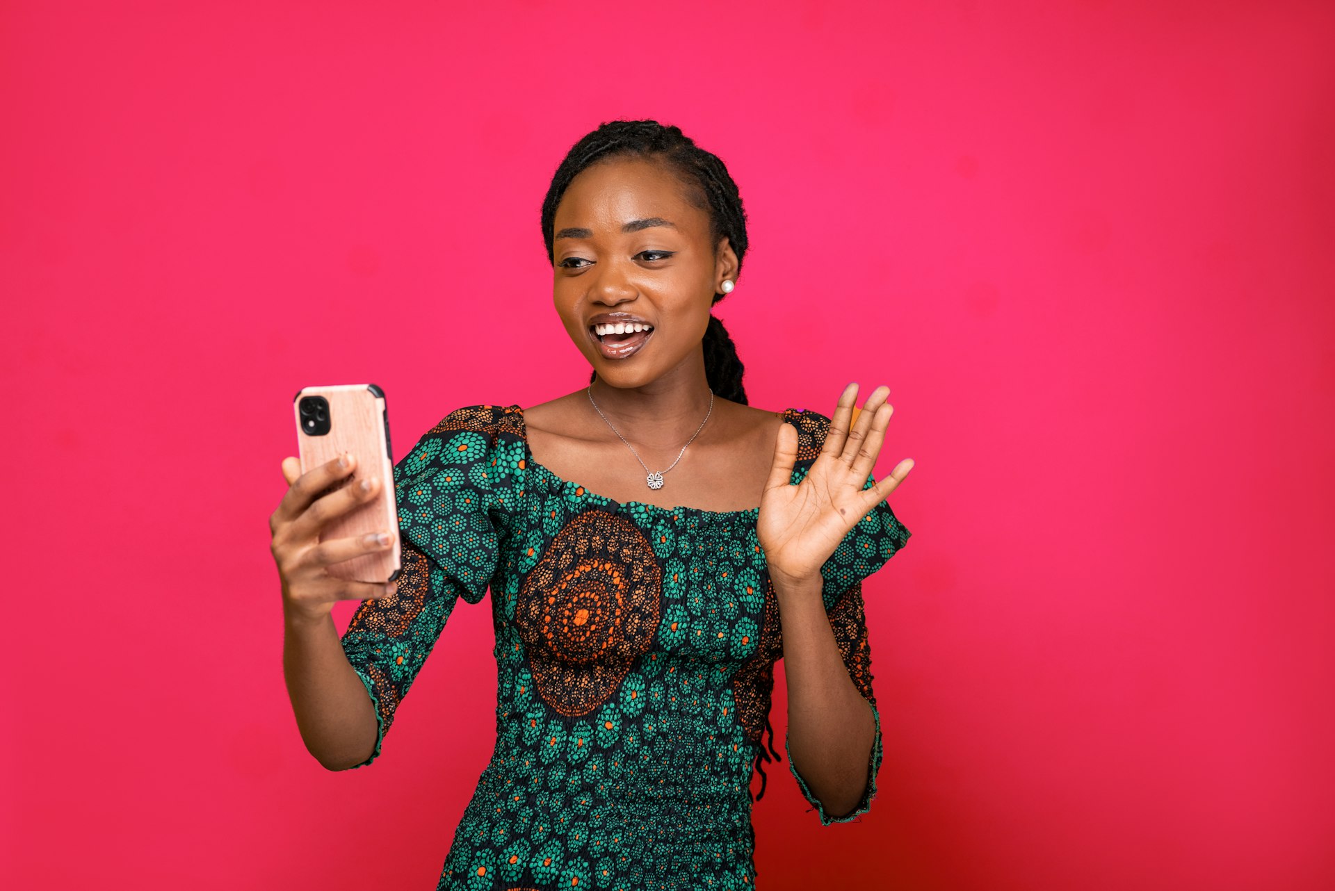 a woman holding a cell phone in front of a pink background